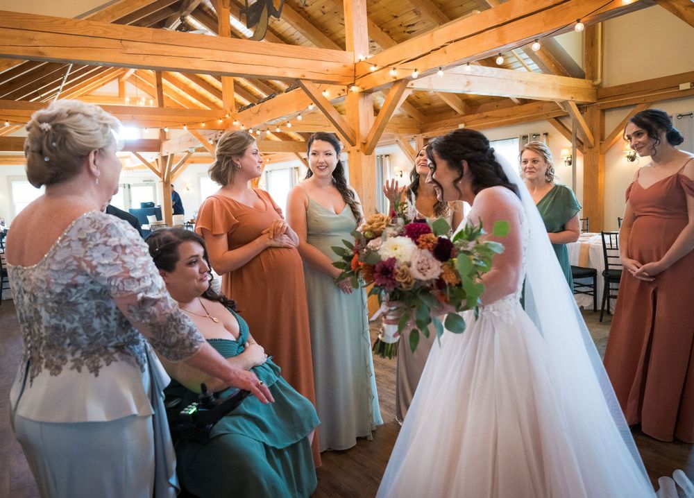 Wedding party members gather in a rustic wooden beam reception hall during celebration moments.