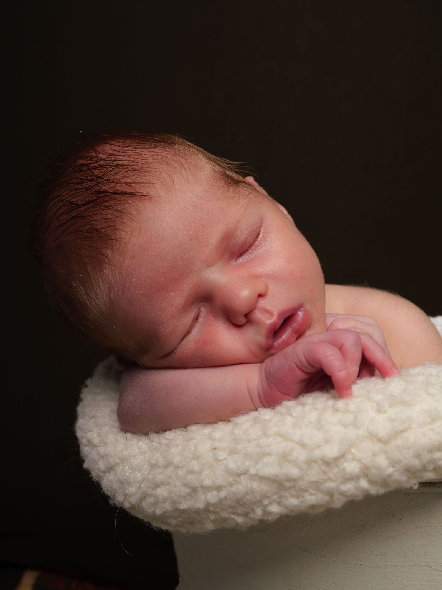 Newborn Photography - A sleeping newborn baby resting peacefully on a soft white blanket.