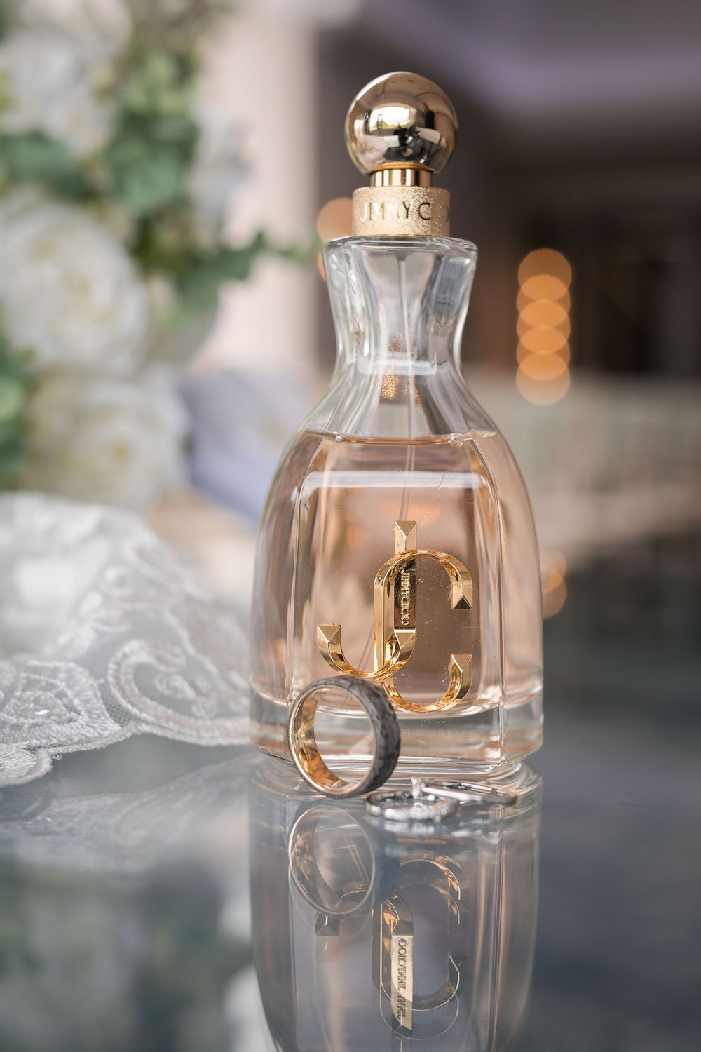 Three perfume bottles with wedding rings artistically displayed with soft bokeh lighting effects.