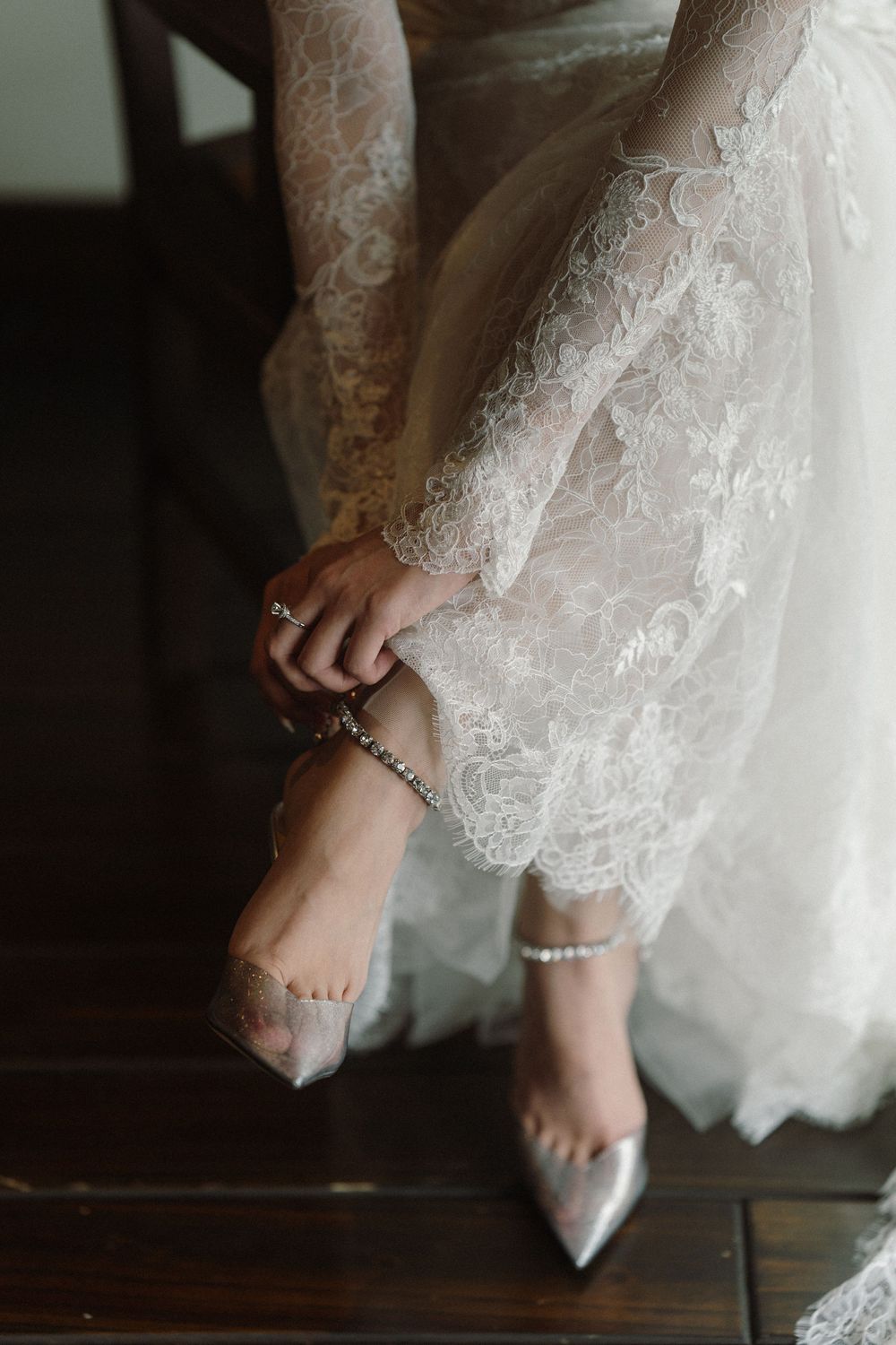 Close-up of an elegant bride's feet wearing silver shoes with pearl ankle decorations.