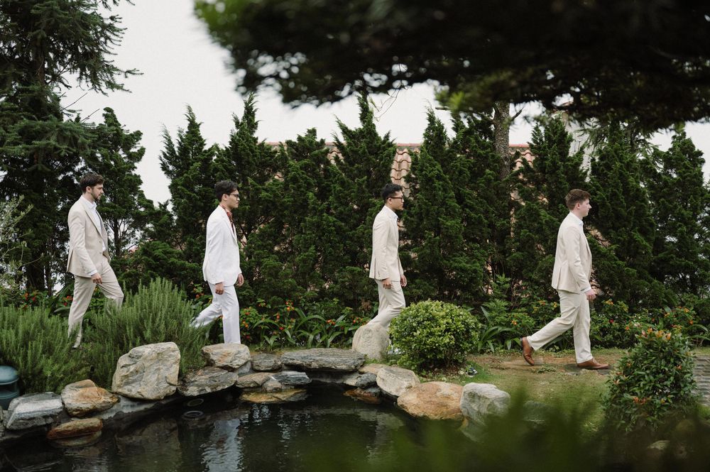 Group walking in white outfits along a garden path beside a decorative pond.