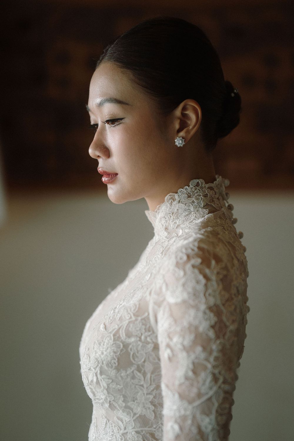 Close-up profile view of an elegant white lace high-neck wedding dress with intricate floral details.