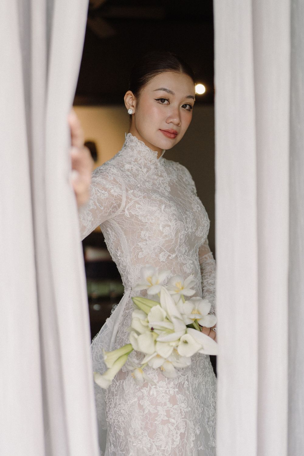 Elegant white qipao dress with intricate lace detailing and white floral bouquet.