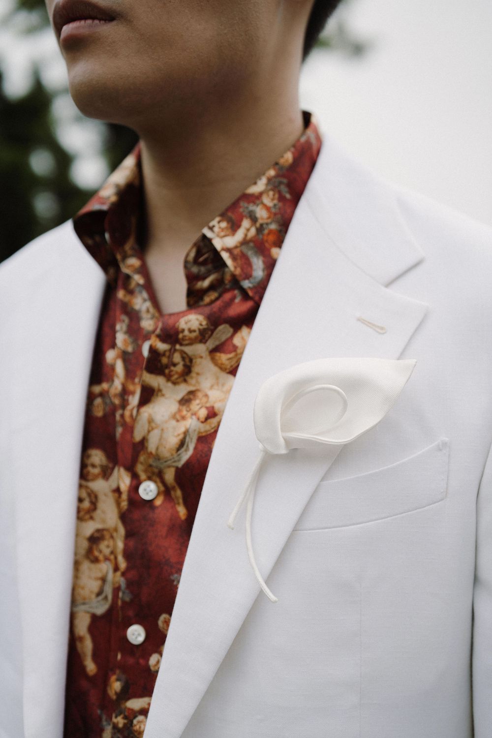 Close-up detail of a white suit jacket with floral print shirt underneath.
