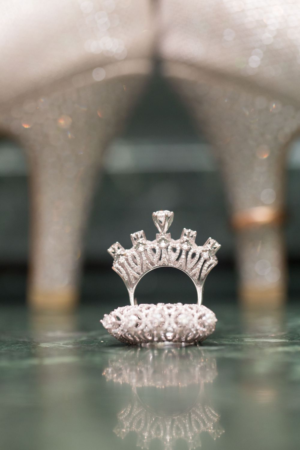 A detailed macro shot sequence of an elegant diamond crown ring reflecting on a glossy surface.