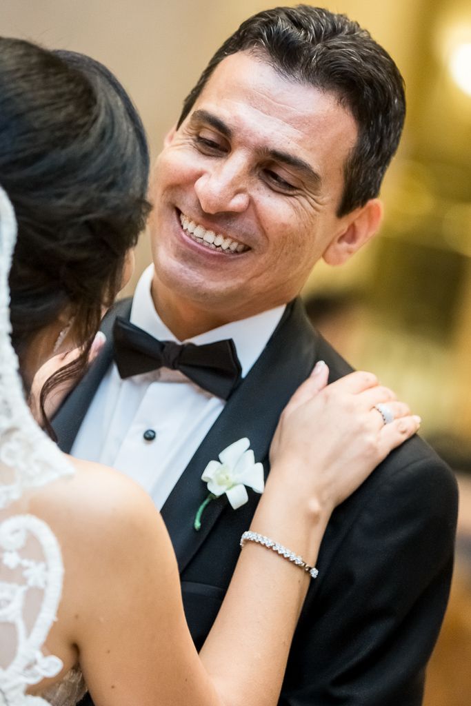 Close-up of groom in black tuxedo smiling during wedding celebration.
