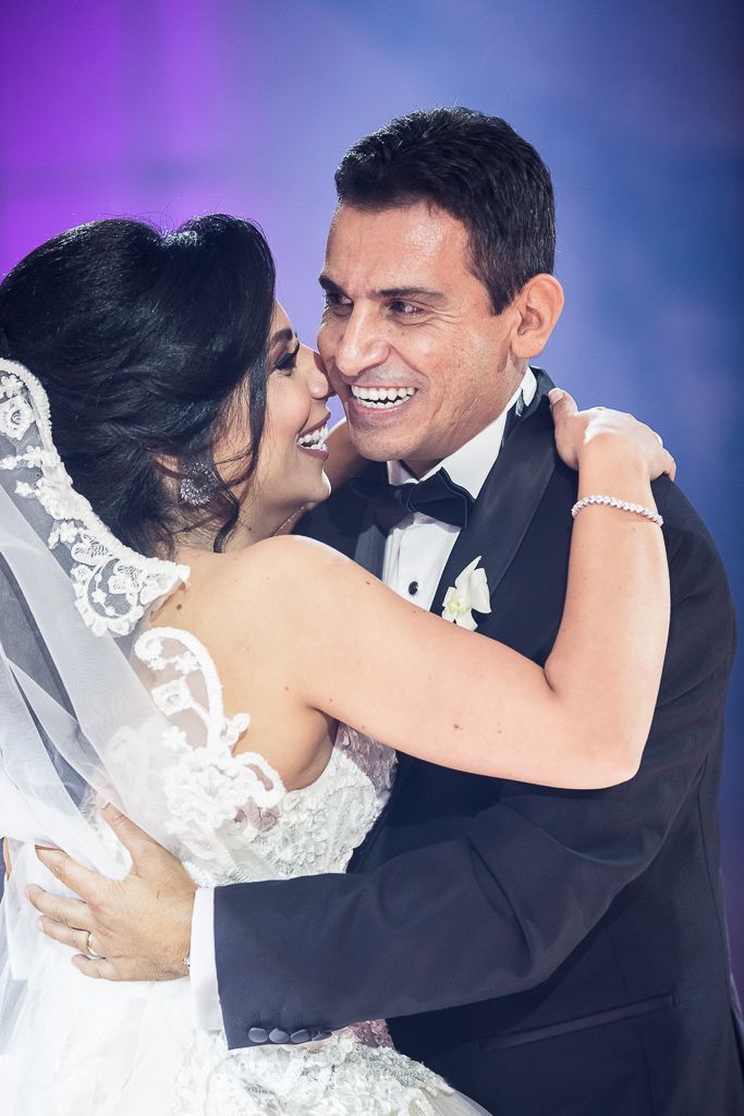 Romantic dance moment between newlyweds with purple and blue lighting effects.