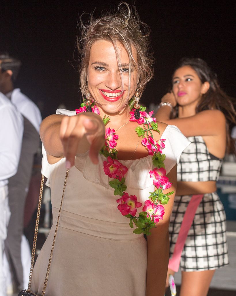 Woman wearing floral lei and beige dress smiling at a party.
