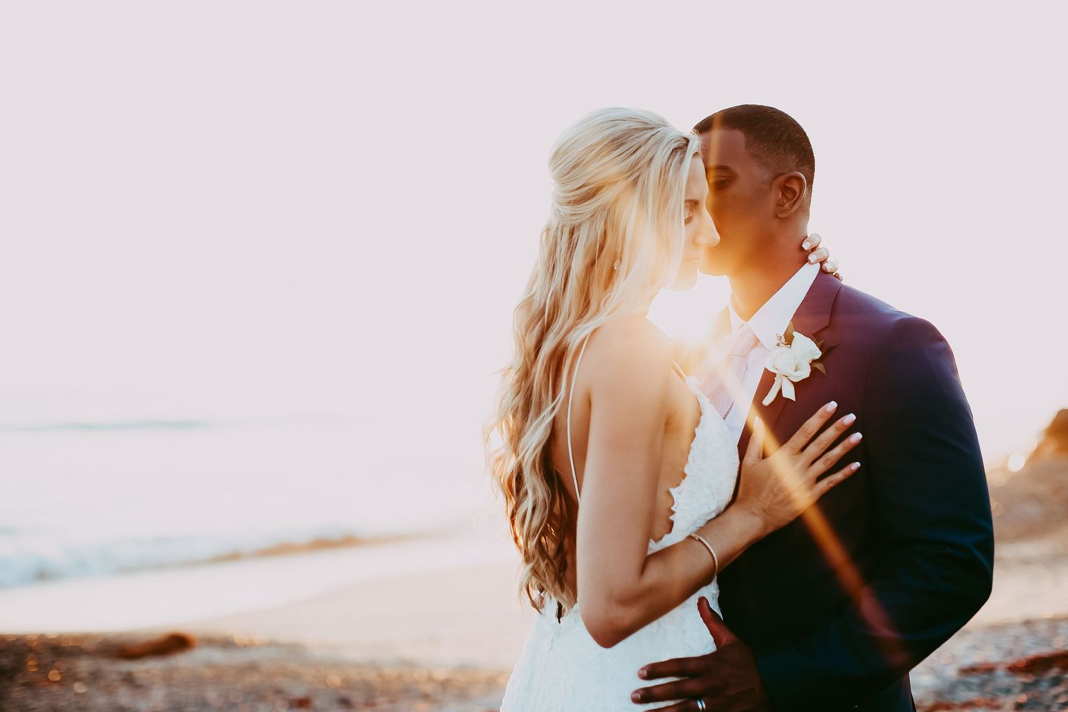 Romantic sunset wedding portrait with golden light streaming through on beach in Orange County.