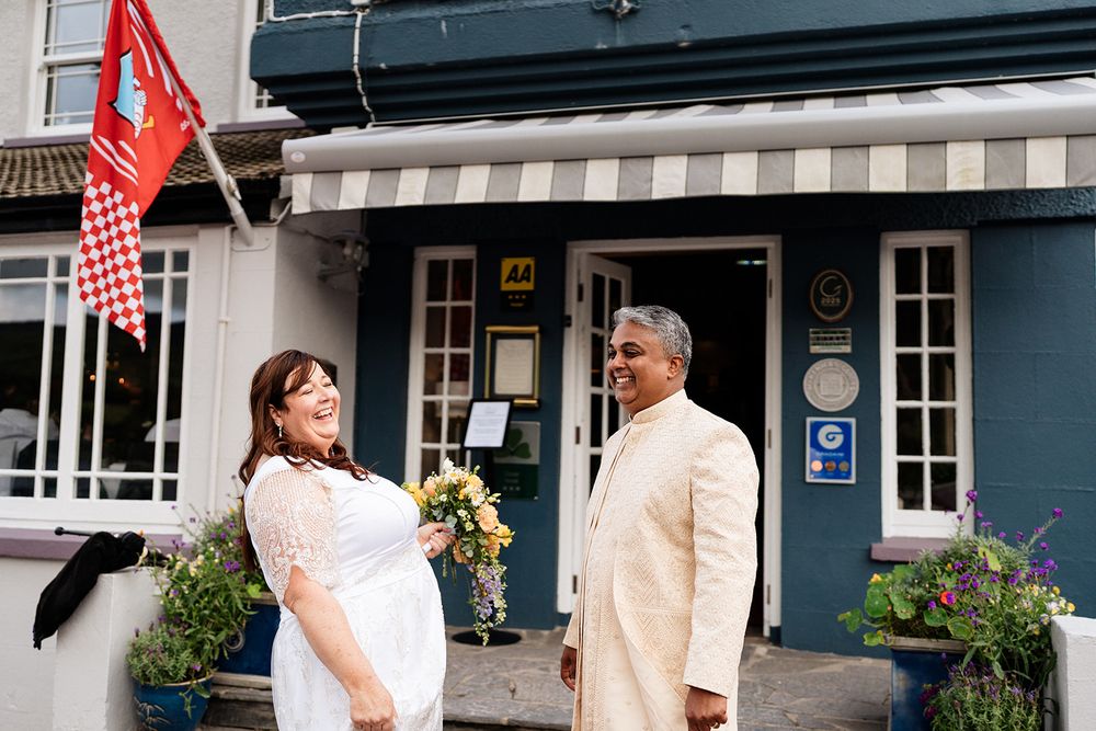 Two people in sunlit open doors look at menu boards on the walls of a restaurant entrance.