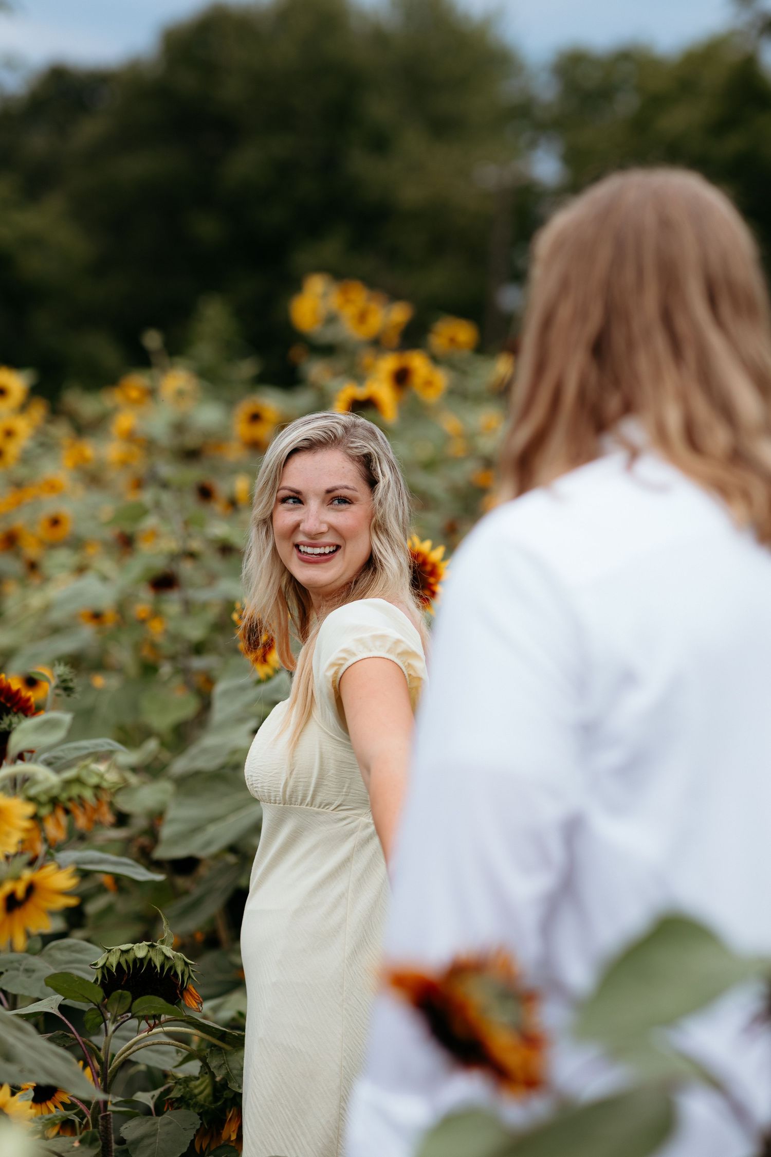 Candid moments in a sunflower field with soft natural lighting and joyful expressions. Engagement couples session.