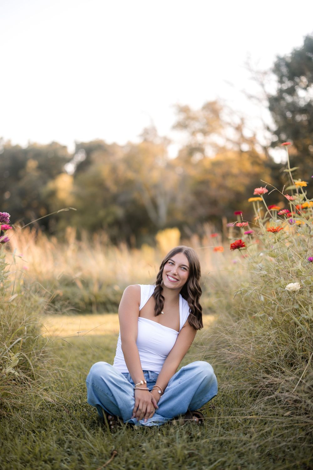 A person sits cross-legged in a grassy meadow with wildflowers during golden hour.