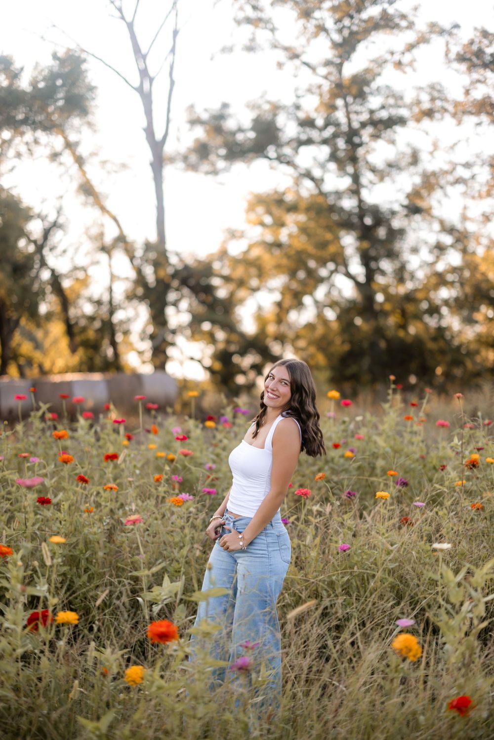 Woman enjoying golden hour in a wildflower meadow with colorful poppies and native plants at sunset.