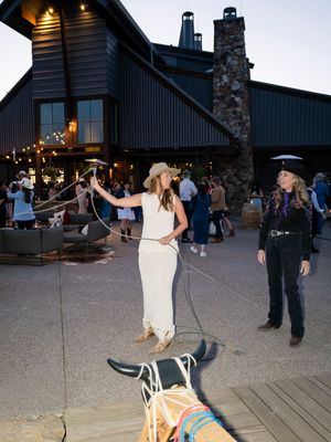 People practicing rope tricks outside a rustic mountain lodge at dusk.
