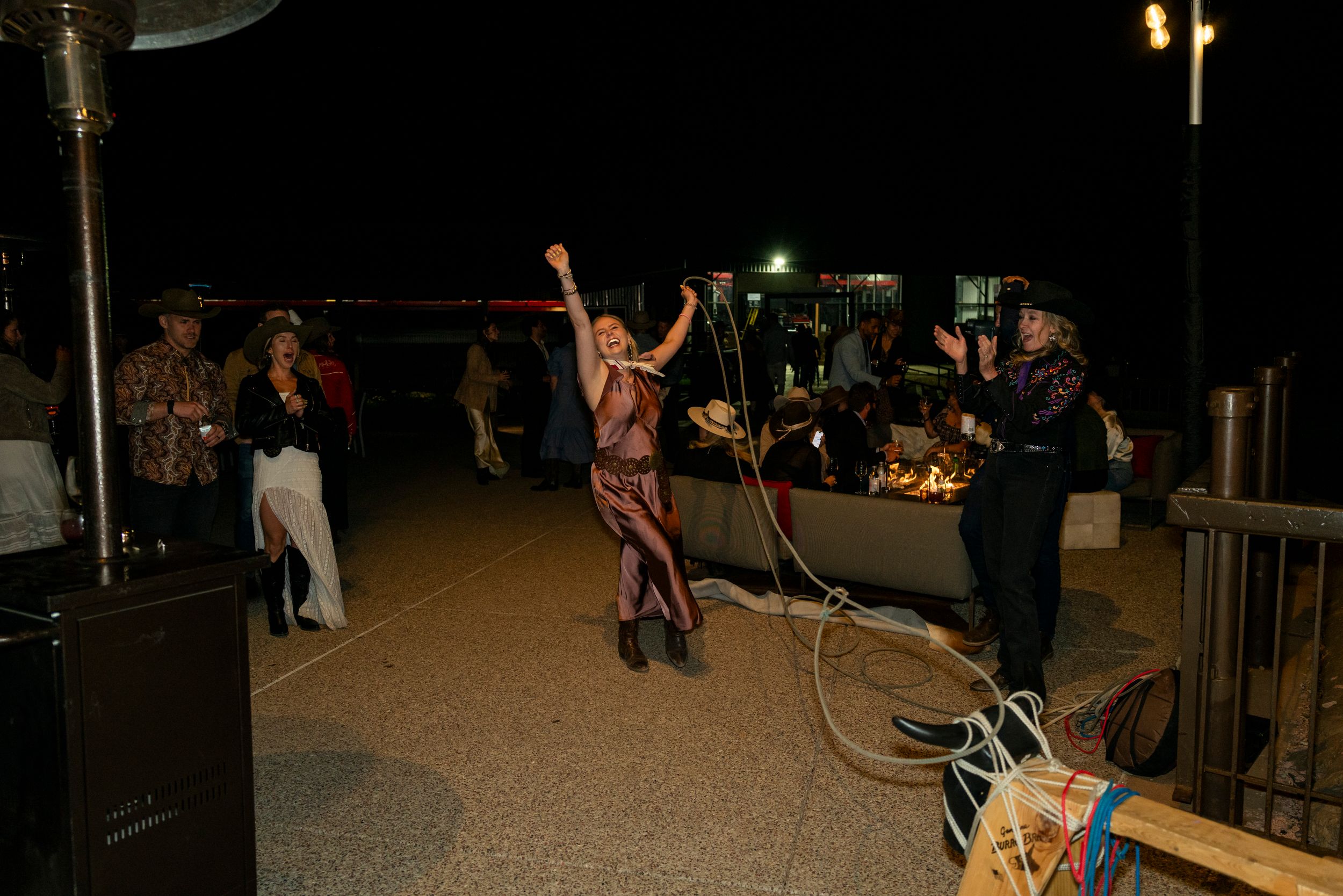 Outdoor nighttime party scene with string lights and people gathered on a patio.