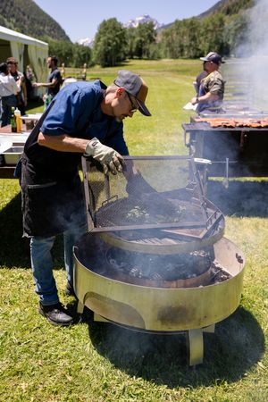 Large outdoor grills smoking during daytime cooking event in mountain setting.