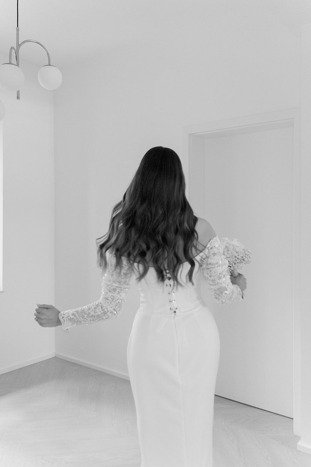 Woman in white lace dress spinning in an all-white minimalist room.