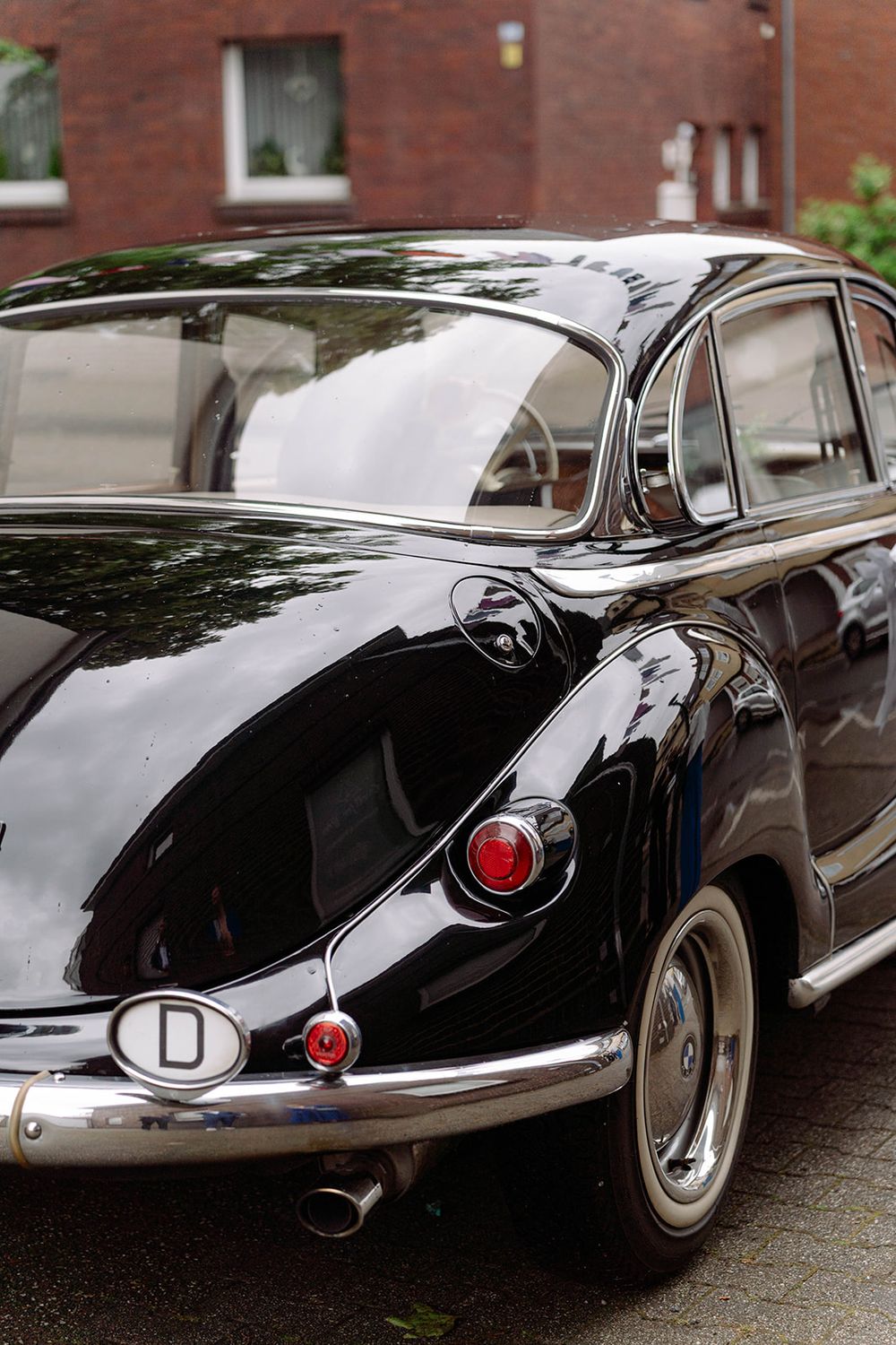 A sleek vintage black BMW car shown from multiple angles on a wet street.