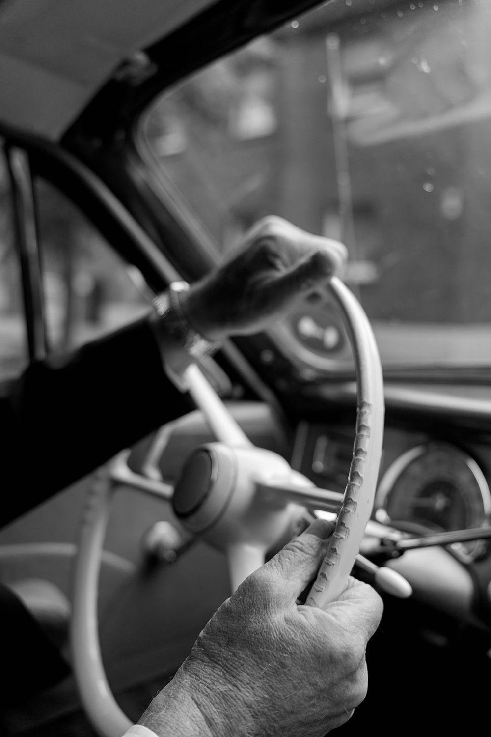 Black and white close-up shots of hands on a steering wheel while driving.