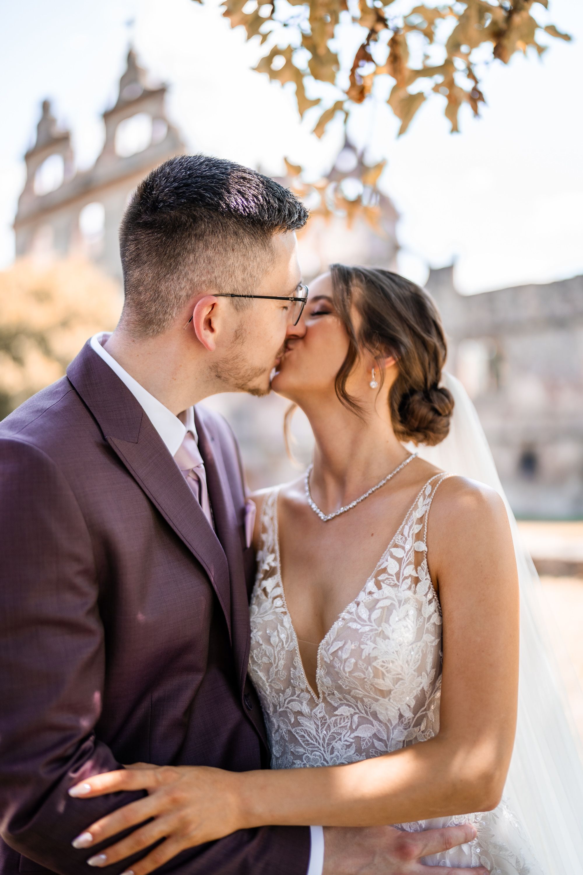 Romantic wedding couple sharing intimate kiss in front of historic building.