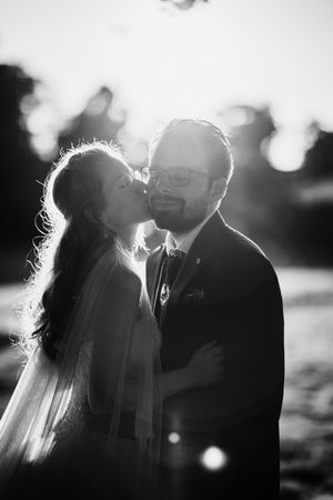 Black and white intimate wedding portrait backlit by sunset.