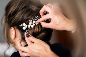 Close-up of delicate white floral hair accessory being placed in bridal hairstyle.