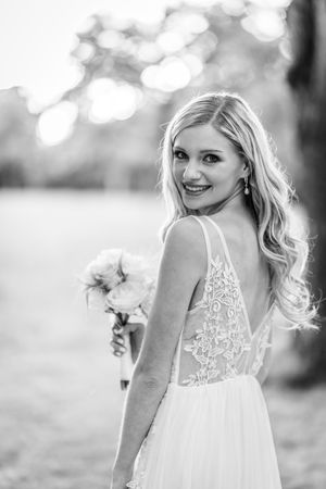 Black and white bridal portrait with bokeh background and lace dress detail.