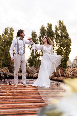 Couple dancing together on wooden deck with bohemian rugs and cushions.