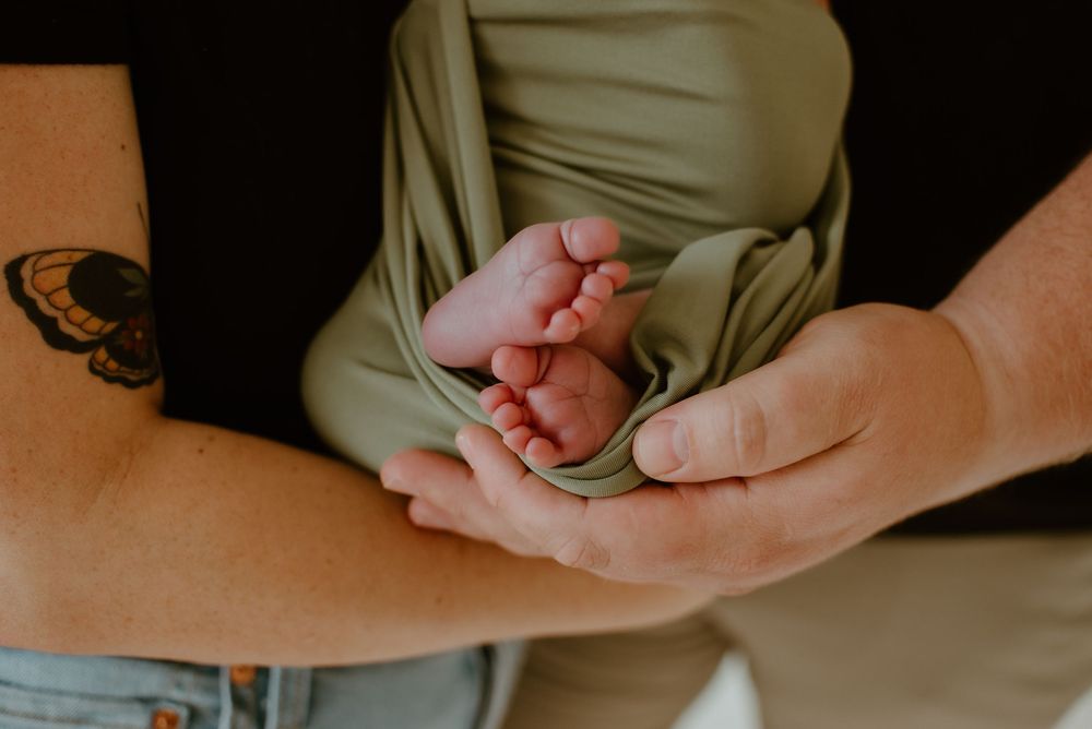 Close-up of tiny newborn feet cradled in gentle hands.