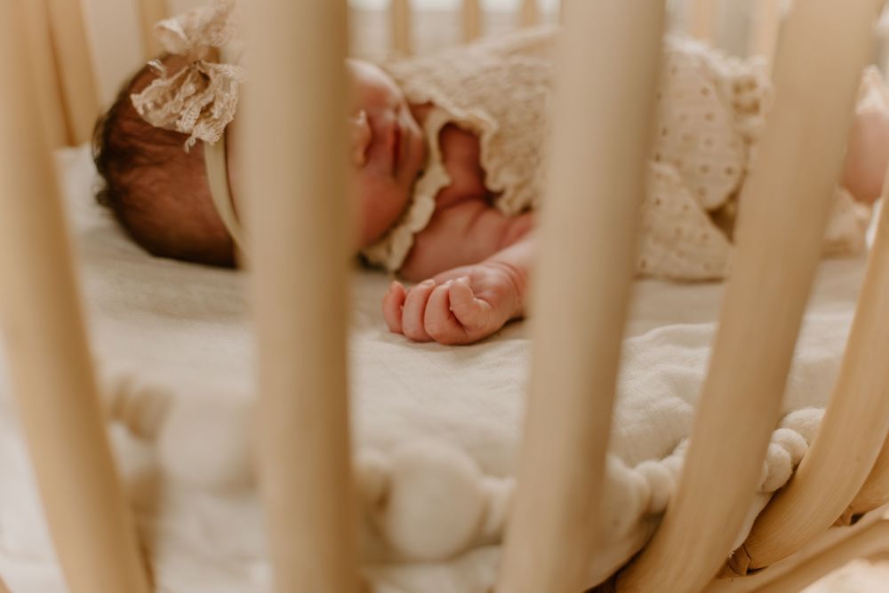 Close-up view through white crib bars of sleeping infant.