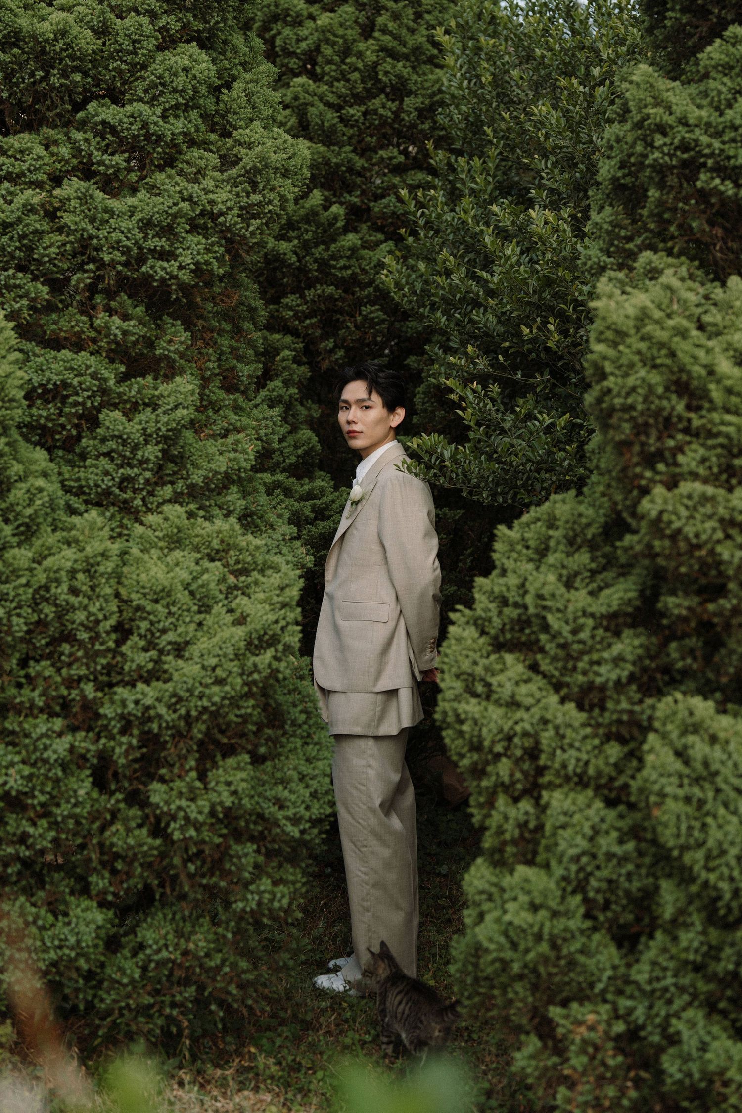 Elegant portrait in a lush garden setting with greenery surrounding the subject.