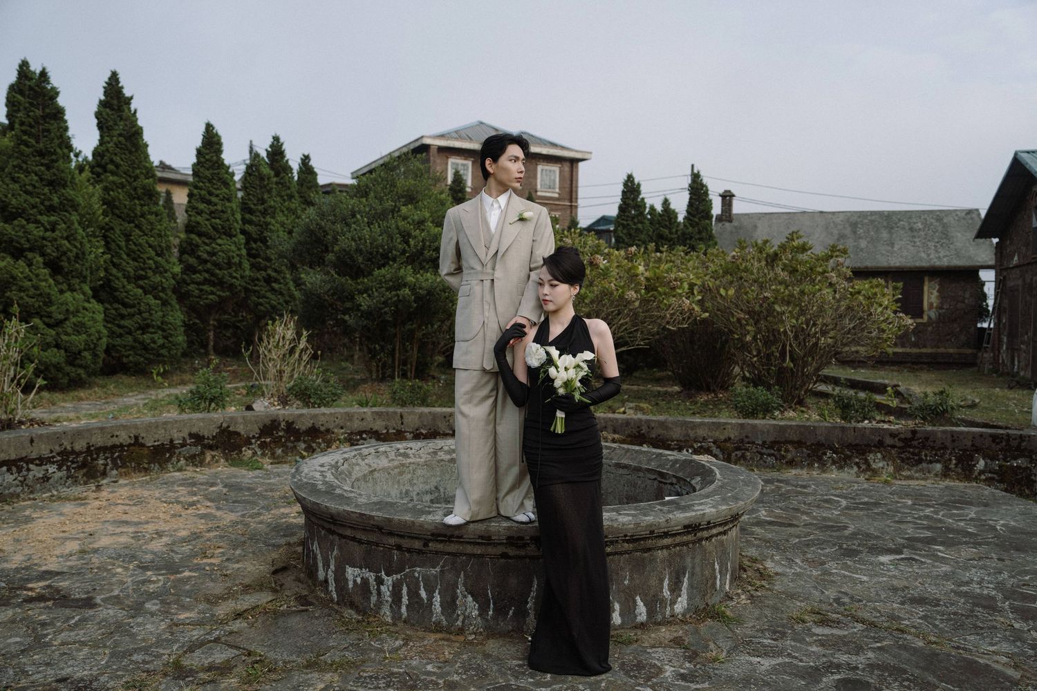 A romantic outdoor photoshoot against a backdrop of stone walls and cypress trees.