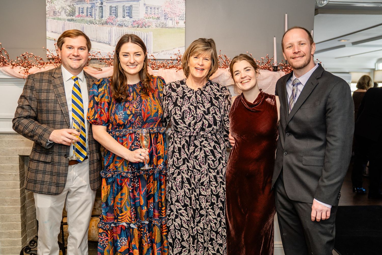 A group of people in formal attire posing together at an indoor event with brick walls visible in the background.