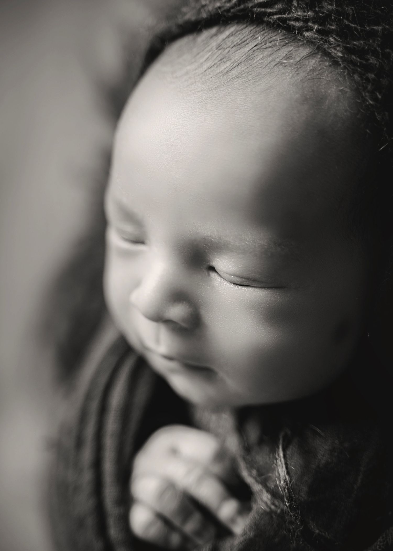A black and white portrait of a baby smiling and laughing in a candid photo series.