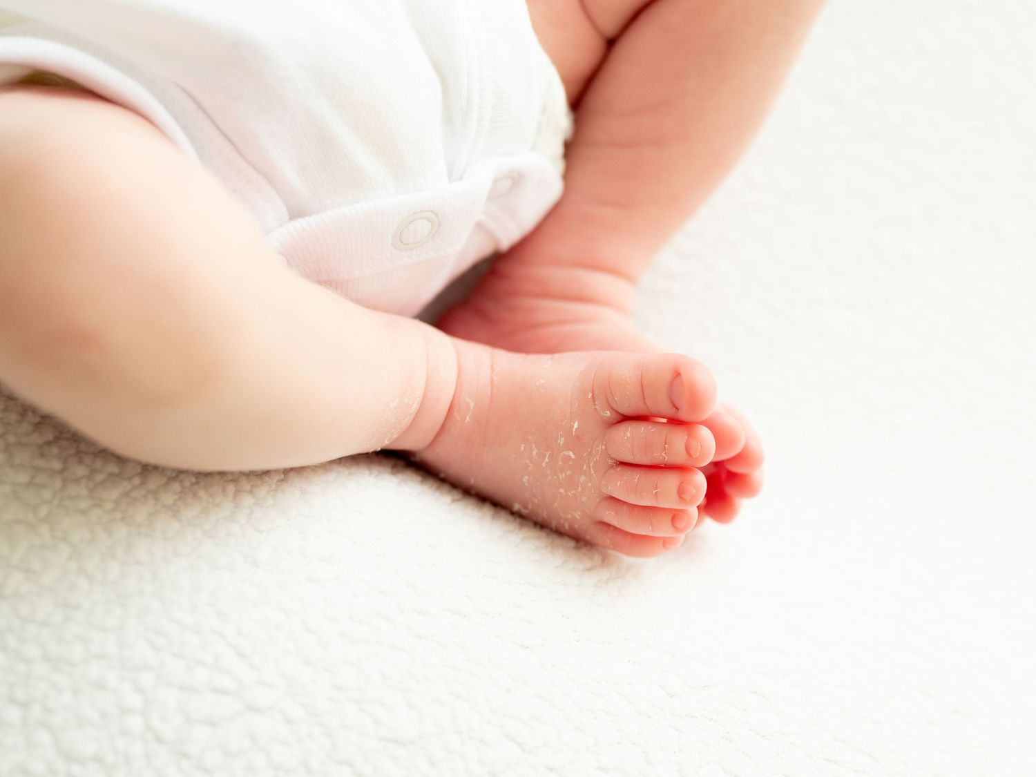 Sweet newborn baby feet close-up series showing various angles and poses on soft white carpet backdrop.