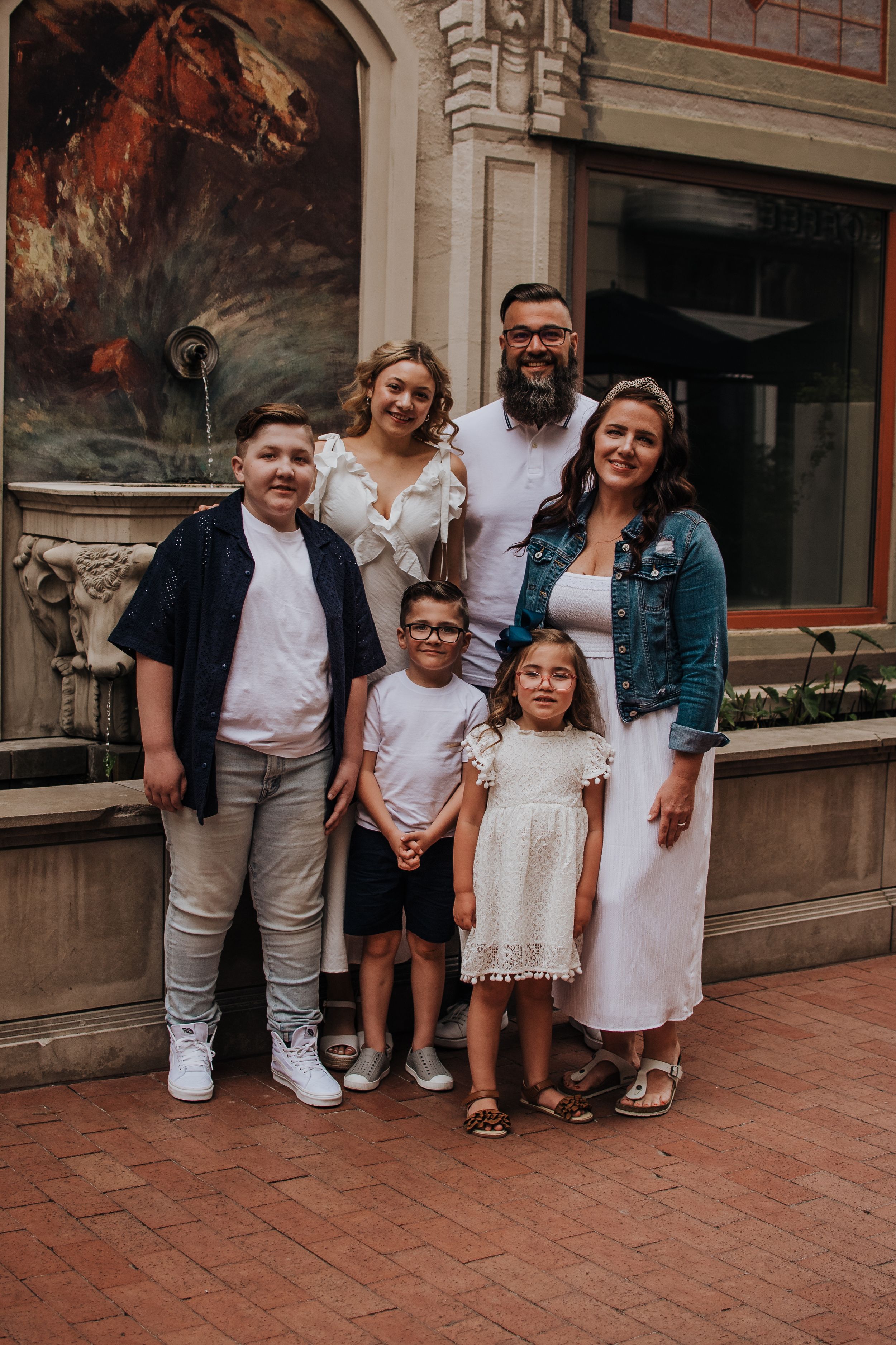 Family members pose casually together on a brick patio outside a storefront.