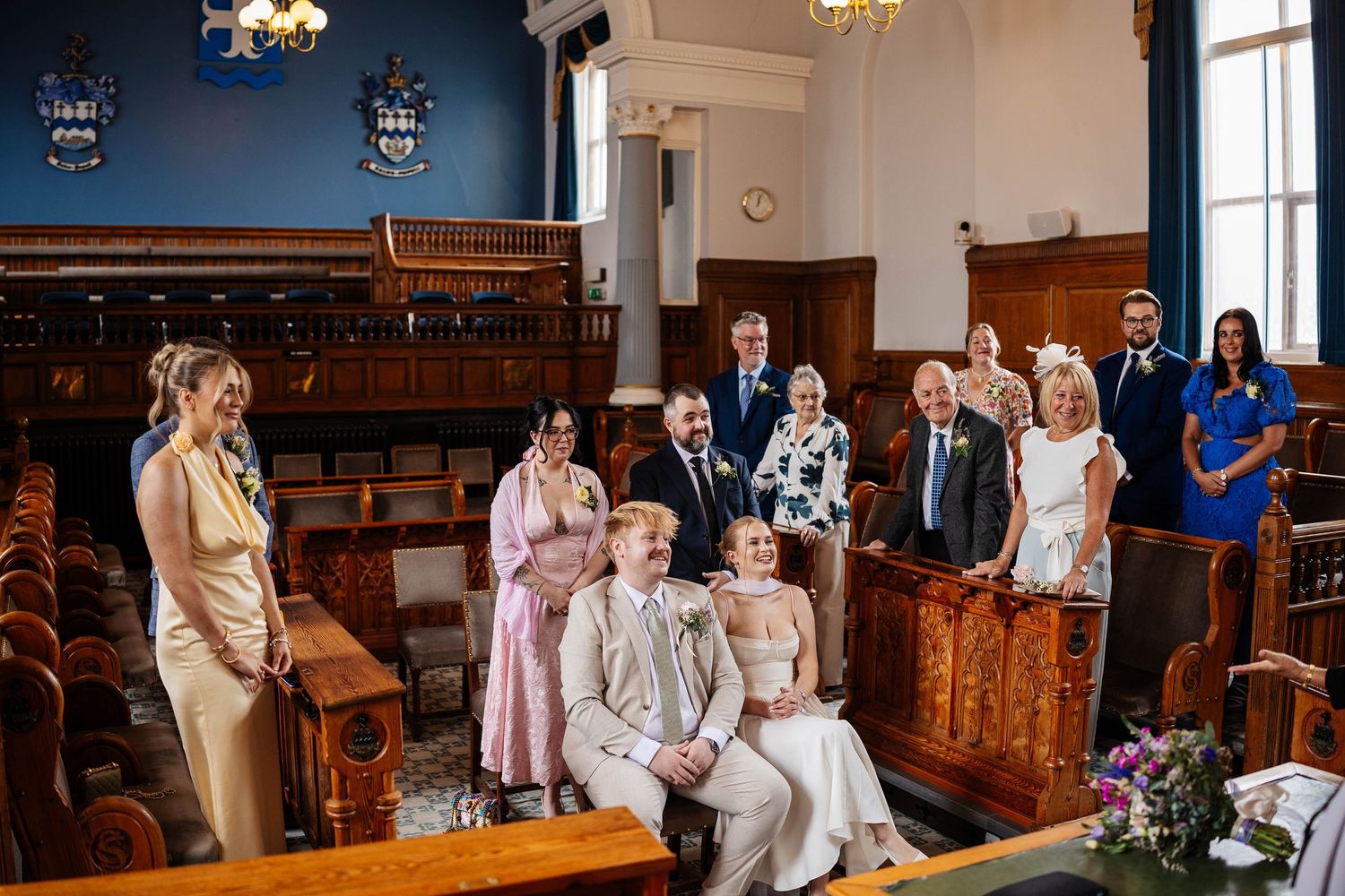 A courtroom ceremony shows guests seated in wooden pews while a couple exchanges vows at Southport Town Hall - Lynette Matthews photography