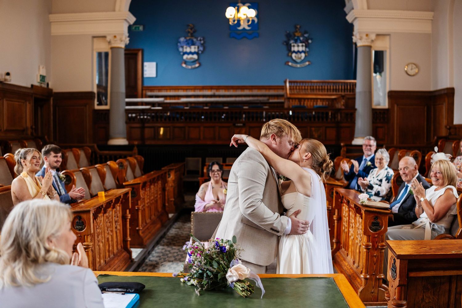Bride & Groom share an intimate moment during a ceremony in Southport Town Hall with blue walls & wooden pews - captured by Lynette Matthews