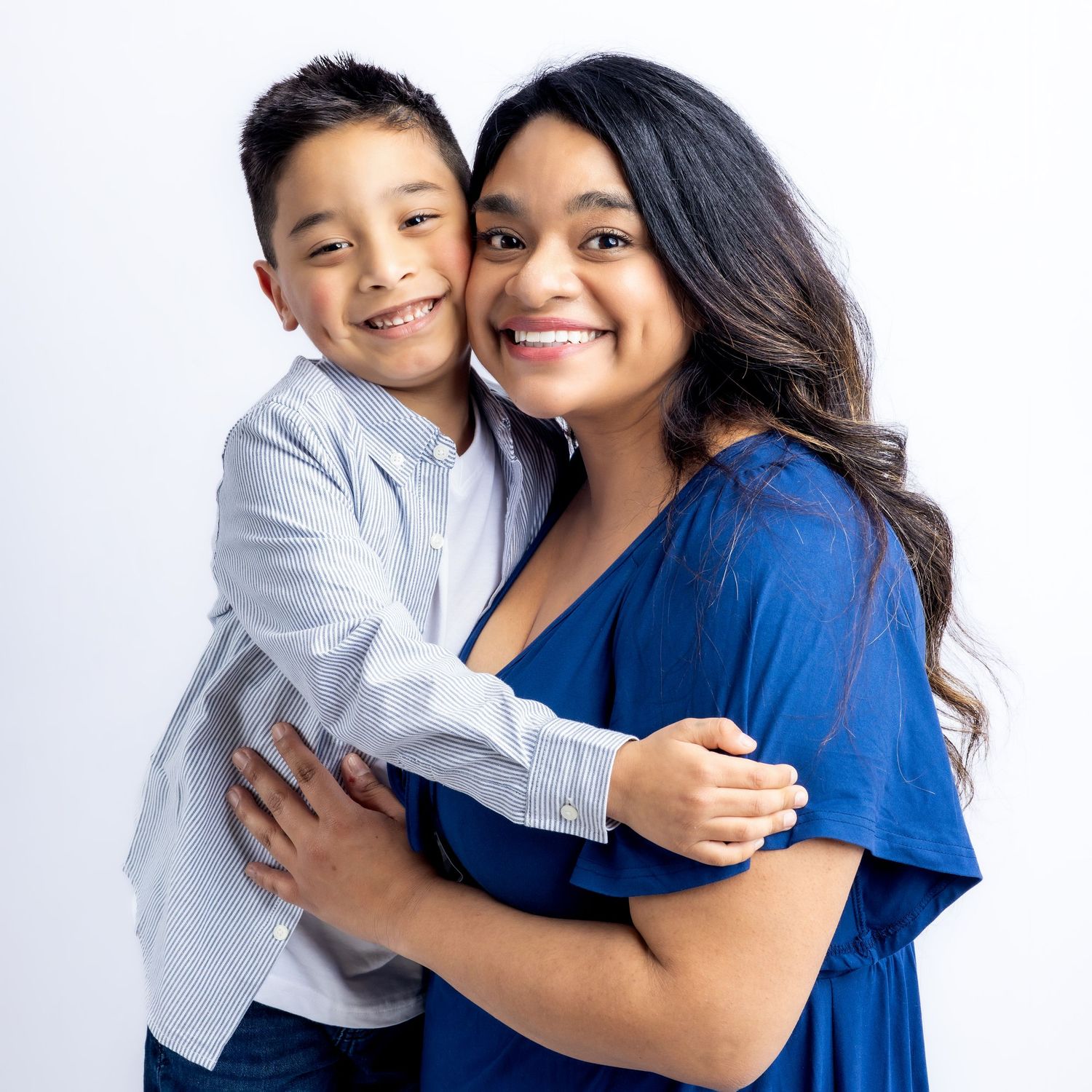A young boy and woman smiling and hugging in a professional portrait against a white background.