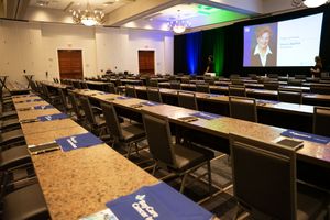 Conference room setup with rows of tables and chairs under modern lighting.