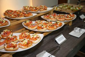 Catering display of appetizers arranged on white plates along a wooden table.