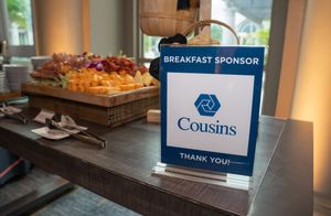Business conference breakfast setup showing tableware, food displays, and sponsor signage in an elegant venue.