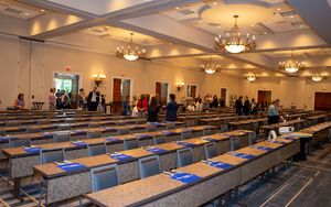 Large conference hall with rows of empty chairs and chandeliers hanging from an ornate ceiling.