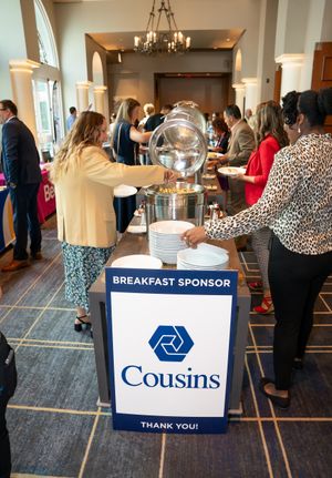 Business networking event showing buffet tables and attendees gathered in a carpeted conference space.