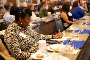 Conference attendee in leopard print taking notes during a business meeting.