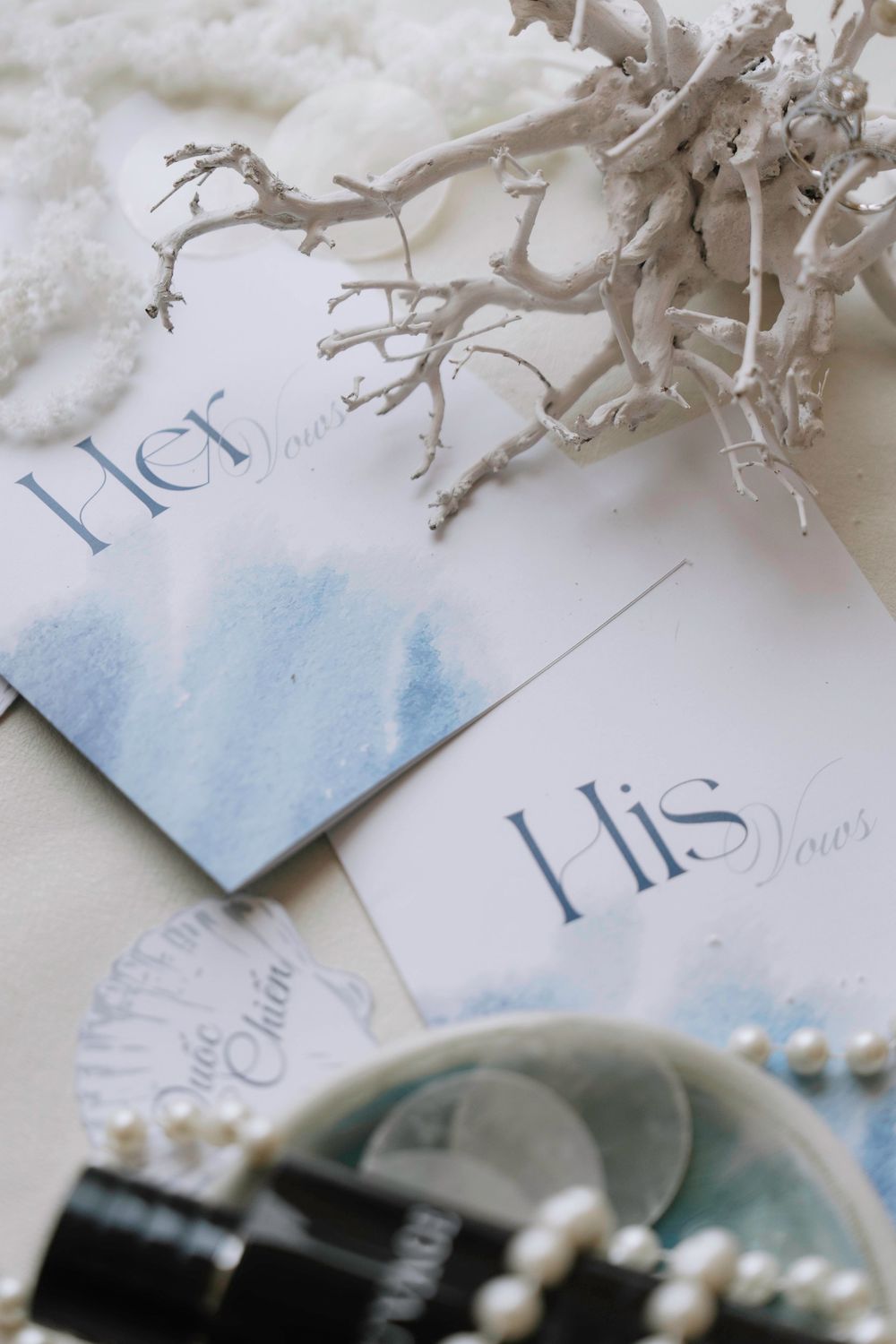His and Her wedding vows cards with pearl jewelry and white branch decoration.