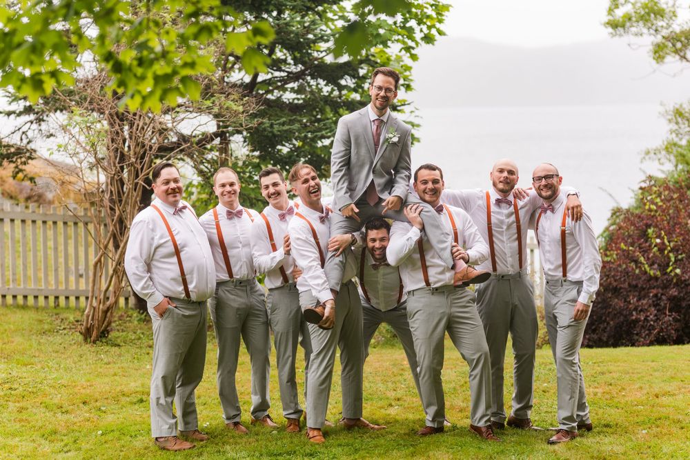 Groomsmen in gray suits and pink suspenders line up for fun photo sequence in outdoor garden venue.