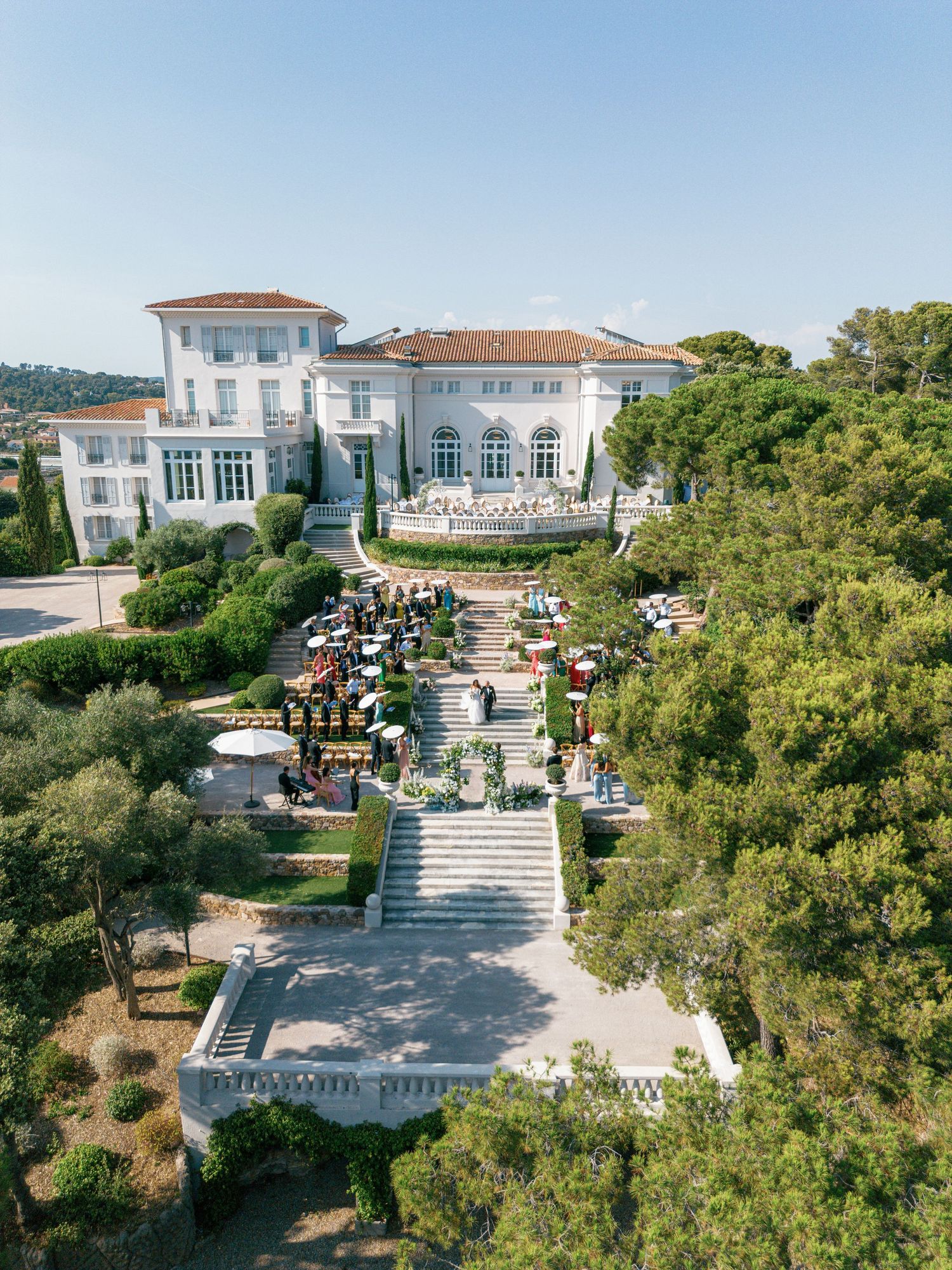 Aerial view of a wedding ceremony surrounded by manicured gardens and trees at Castel Bay, Hyères, French Riviera.
