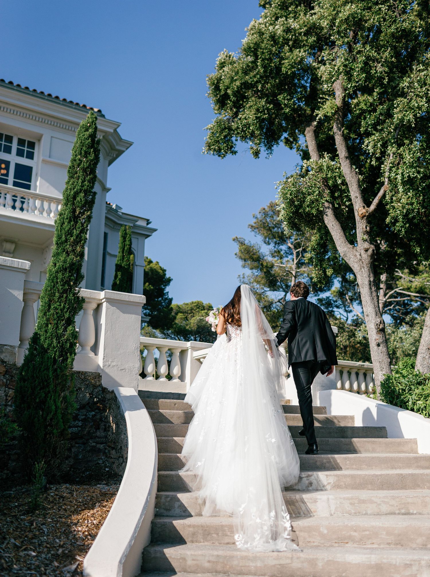Bride and groom walk away at Castel Bay, Hyères, French Riviera.