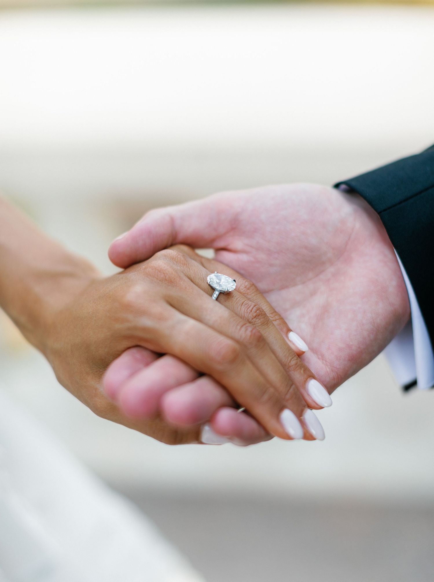 Close-up of hands with engagement ring showing couple holding hands during wedding or proposal moment.